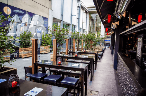 Stylish Urban Patio With Artistic Mural and Lush Greenery for Vibrant Events