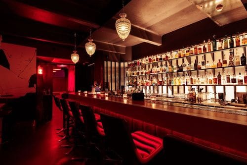 Bold Red Cocktail Bar With Artistic Murals and Ambient Lighting for After-Work Socials