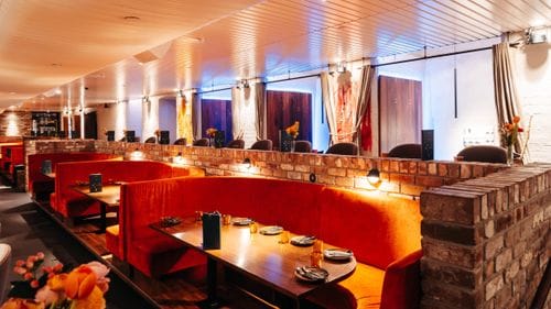 Brick-Lined Lounge With Plush Velvet Booths and Moody Lighting for Sophisticated Gatherings