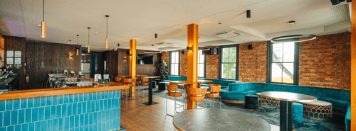 Modern Bar With Teal Lounge and Exposed Brick for Casual Social Events